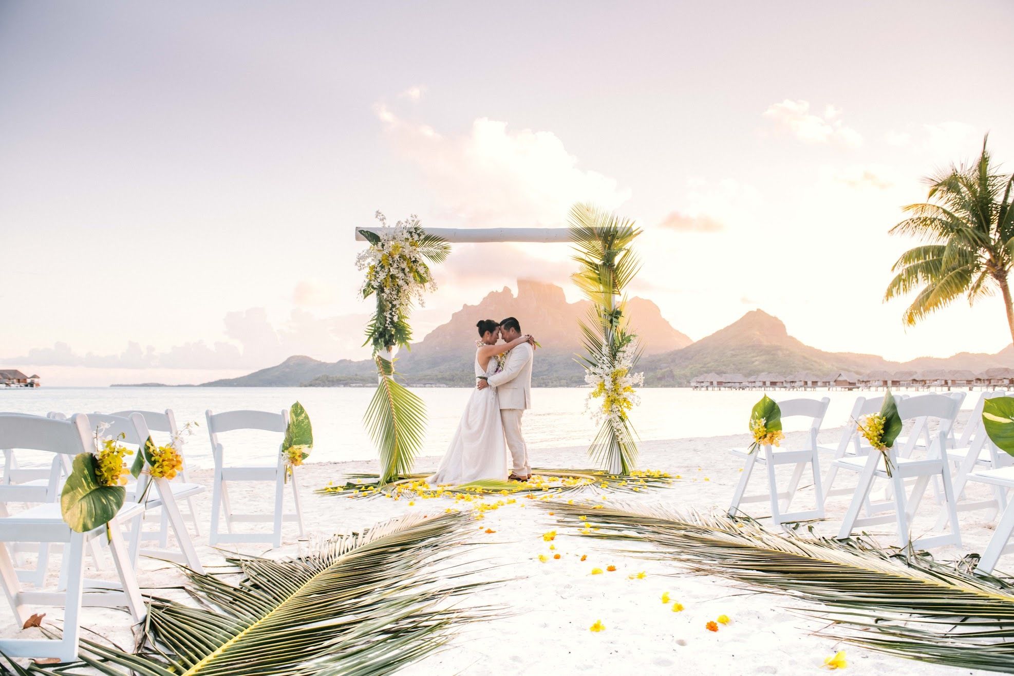 stunning tropical wedding in bora bora four seasons with couple at alter and plam leaves as décor | PartySlate