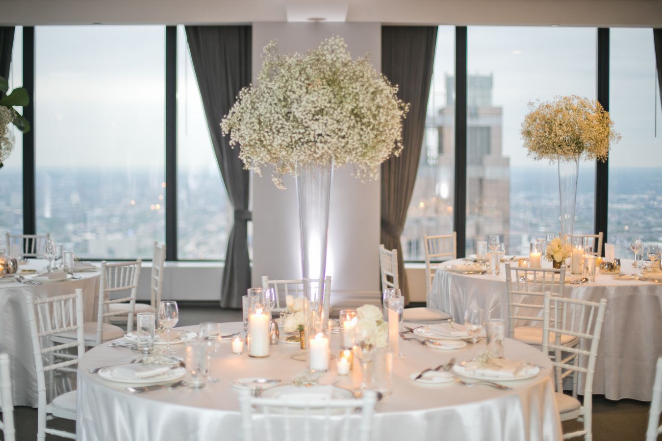 tall babies breath centerpieces on round tables with white table cloths | PartySlate