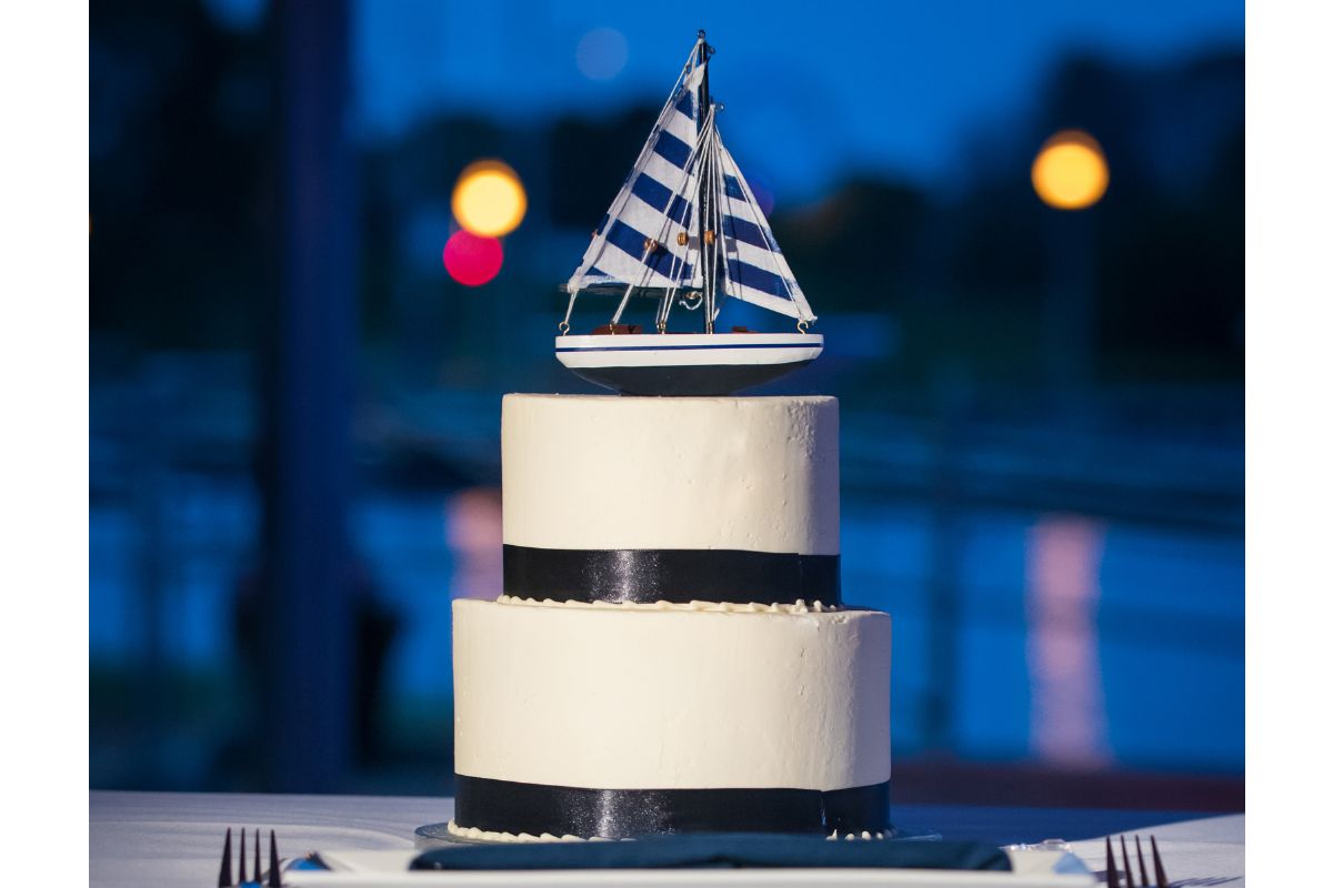 Two tiered cake topped with a blue and white striped sailboat