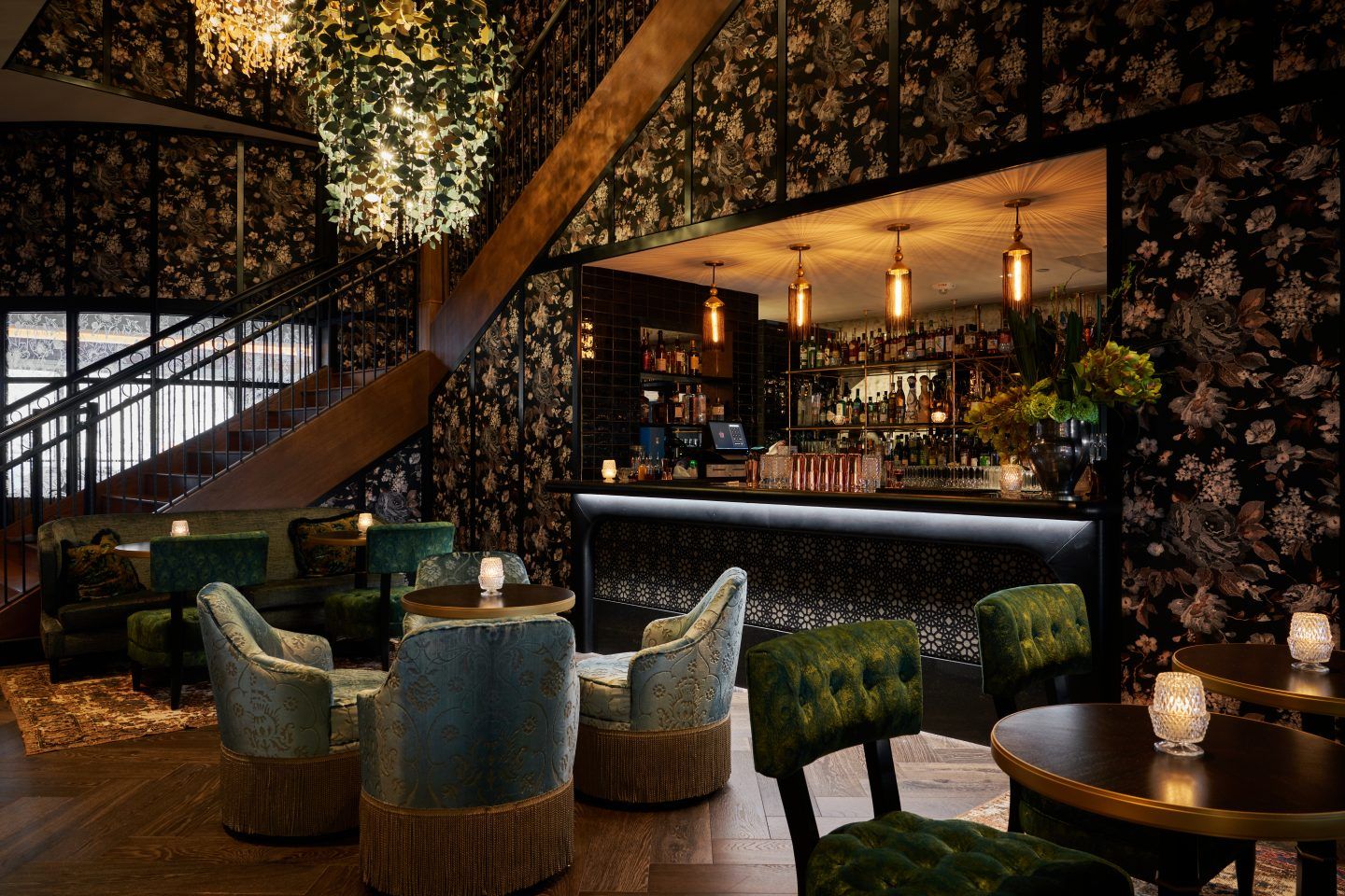 Monarch dining room with dark wood accents and floral wallpaper and cozy velvet chairs and moody lighting | PartySlate