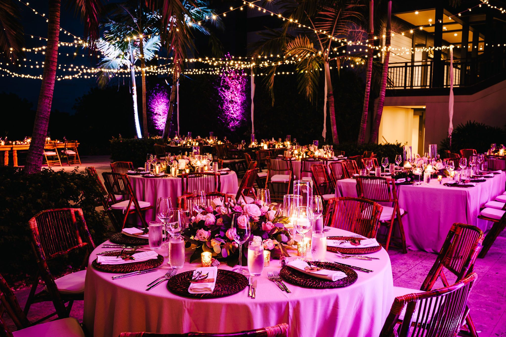 Outdoor wedding reception with pink uplighting and string lights | PartySlate