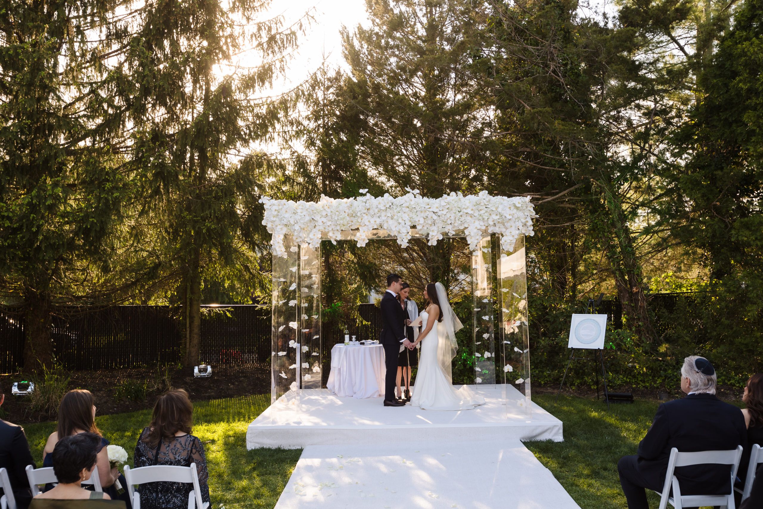 Lucite squared arch at alter with couple getting married and white fabric laid down for the asile | PartySlate