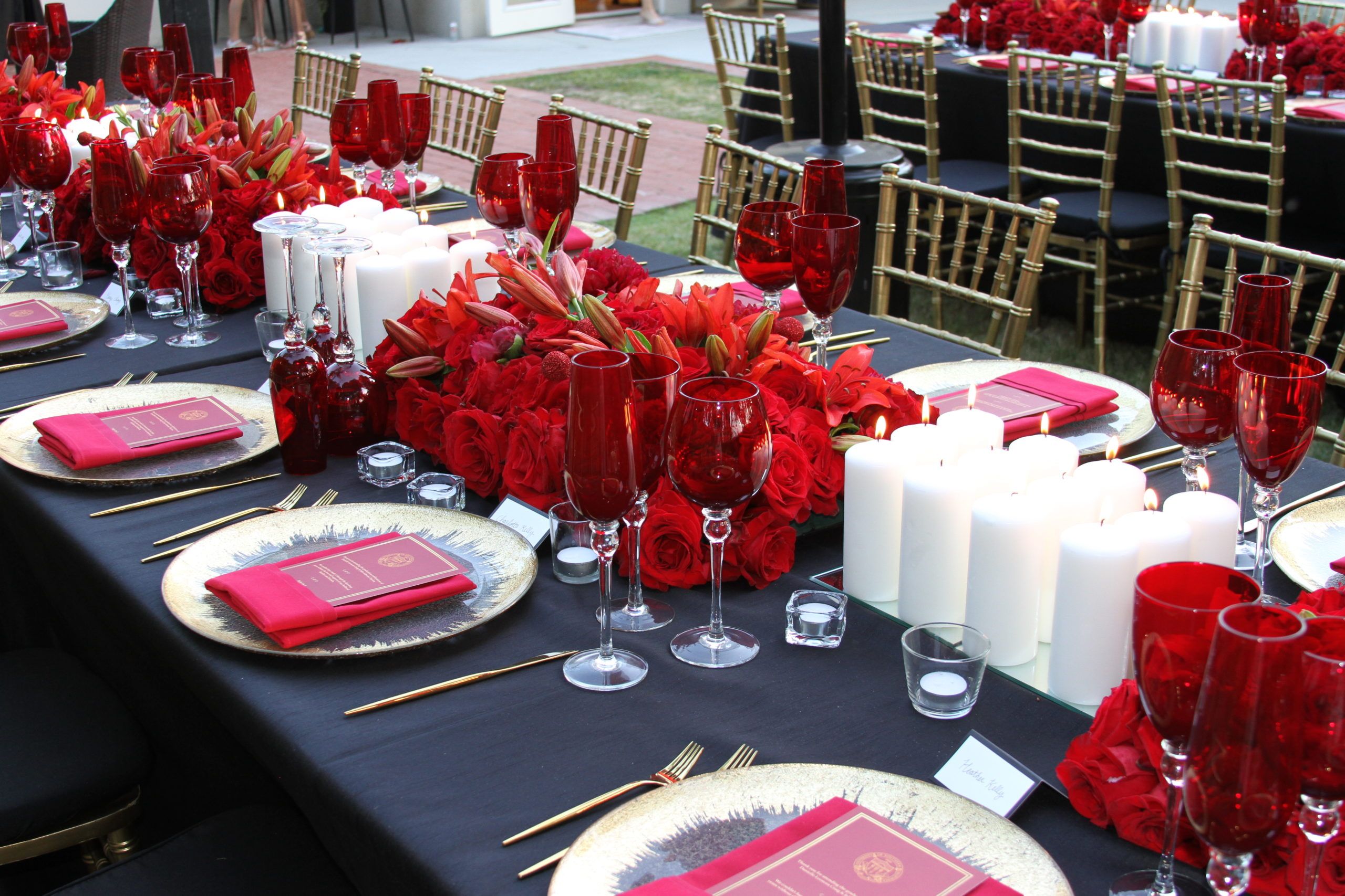 graduation party with red rose centerpieces and red accents on table with black table cloth | PartySlate
