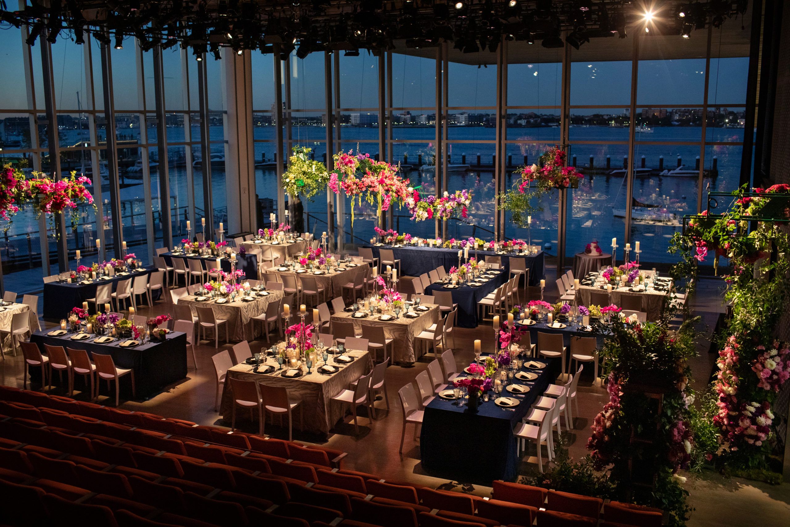 Wedding reception area with dining tables set with linen and colorful floral arrangements on tables | PartySlate