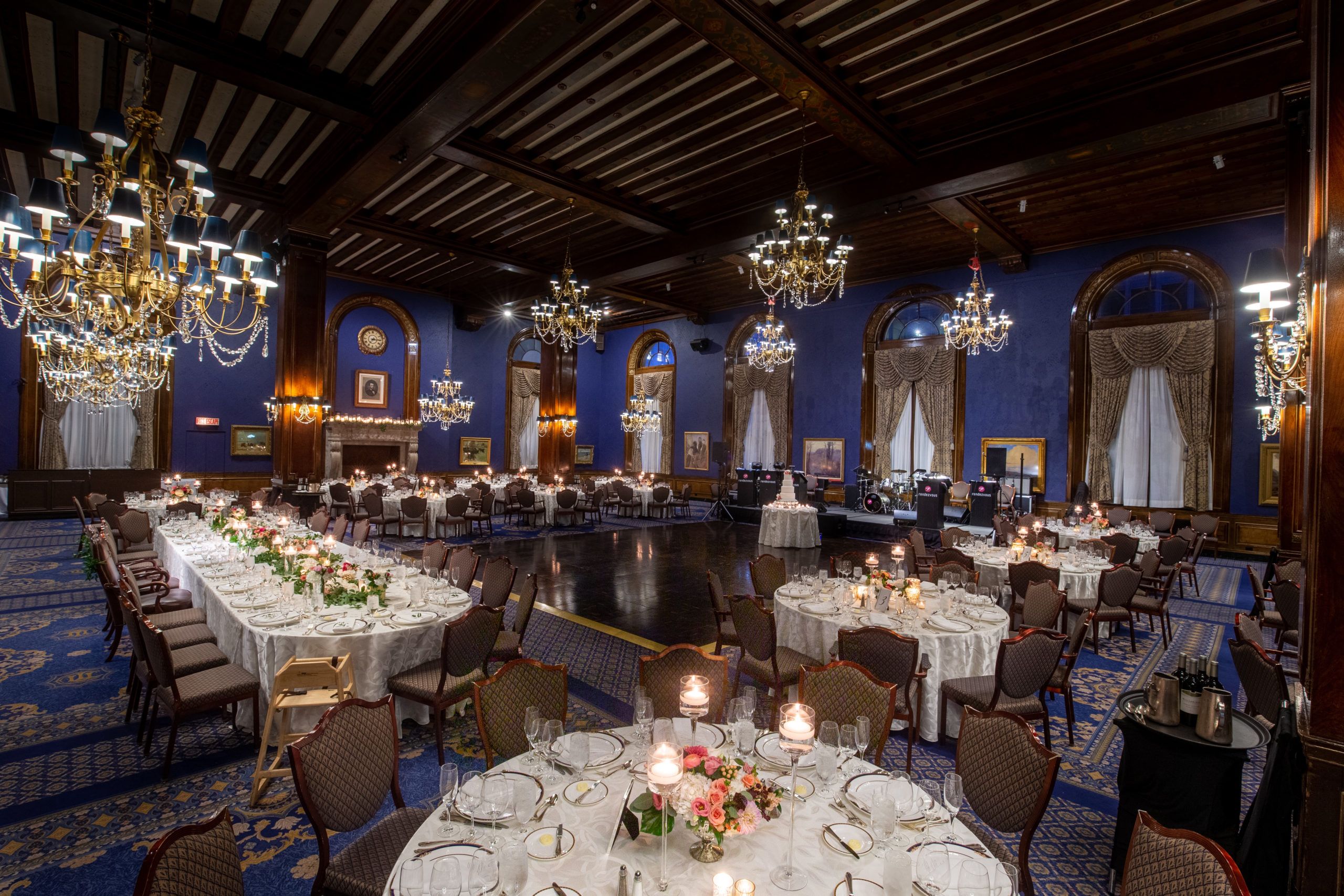 Navy and gold wedding color palette at reception with blue accents on walls and gold place settings on tables | PartySlate