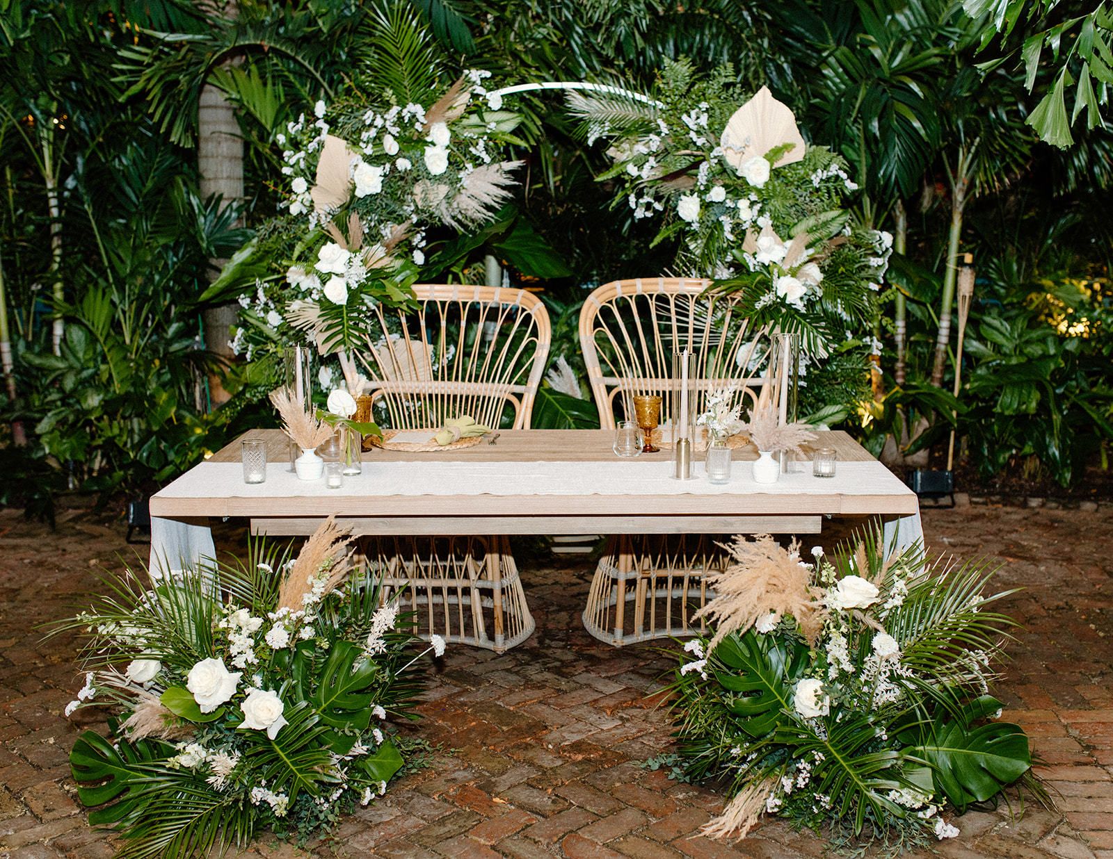 Sweetheart table with rattan seating and monstera leaf décor | PartySlate
