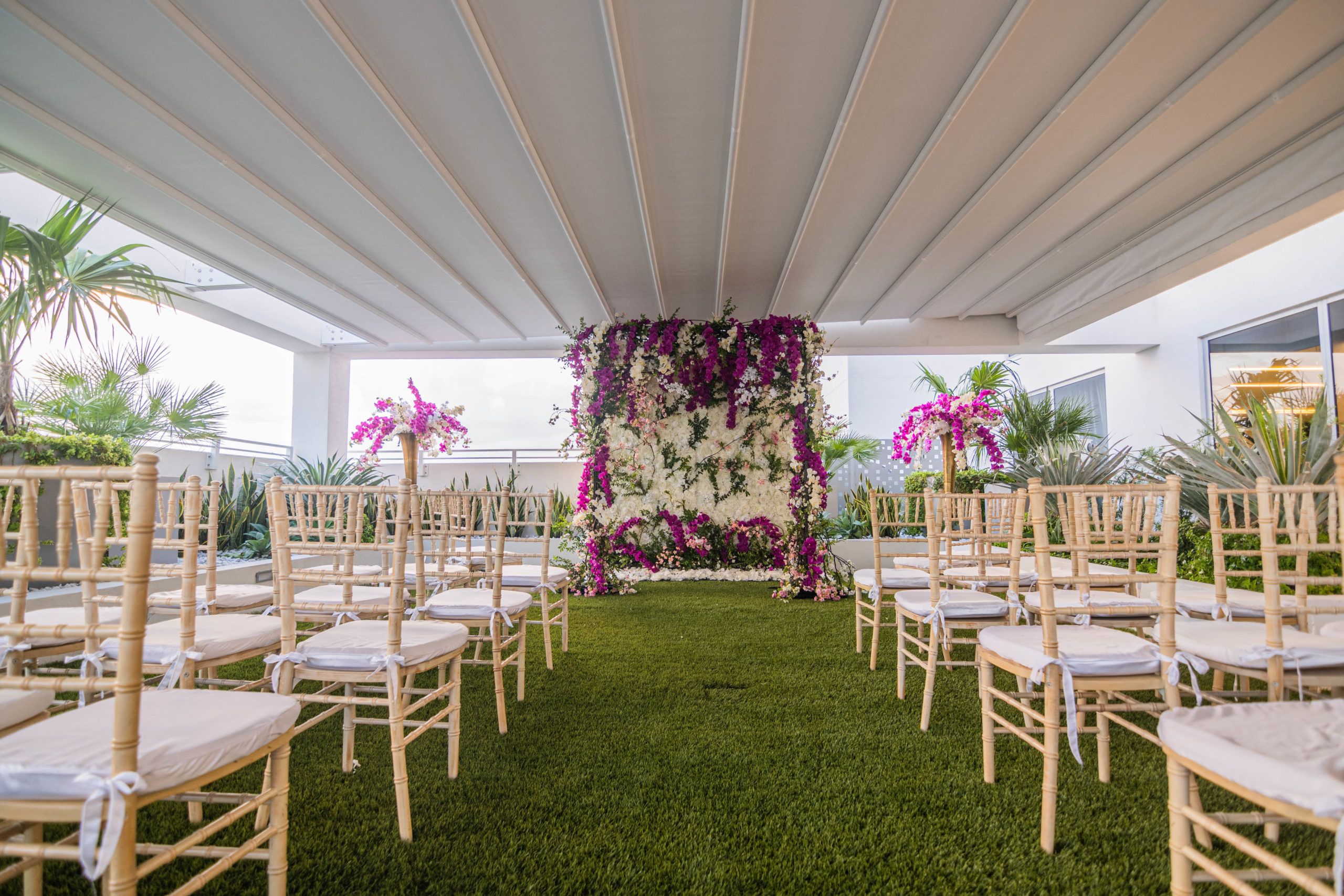 tropical outdoor wedding in miami with floral wall at the end of wedding aisle | PartySlate