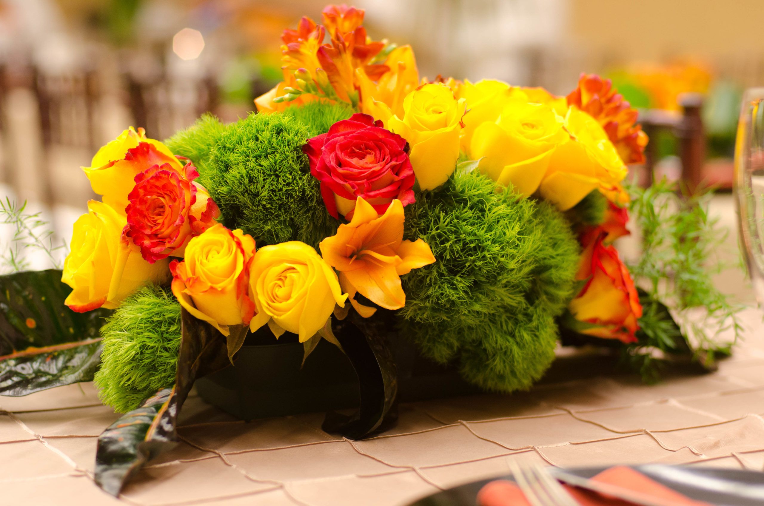 Bright red, orange, and yellow flower centerpiece with bright green moss | PartySlate