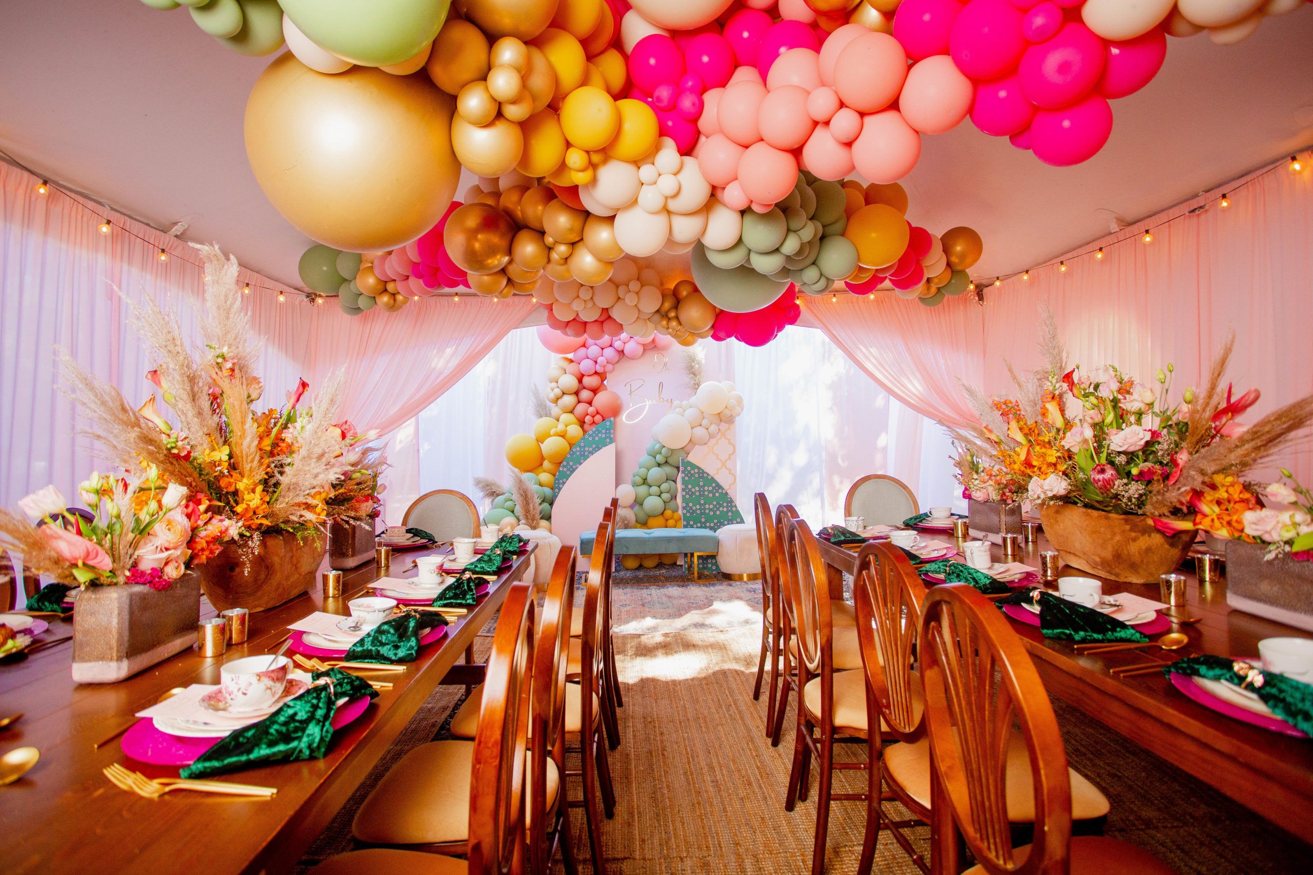 Bright baby shower with boho centerpieces and gold, pink, and pale green ceiling balloon décor | PartySlate