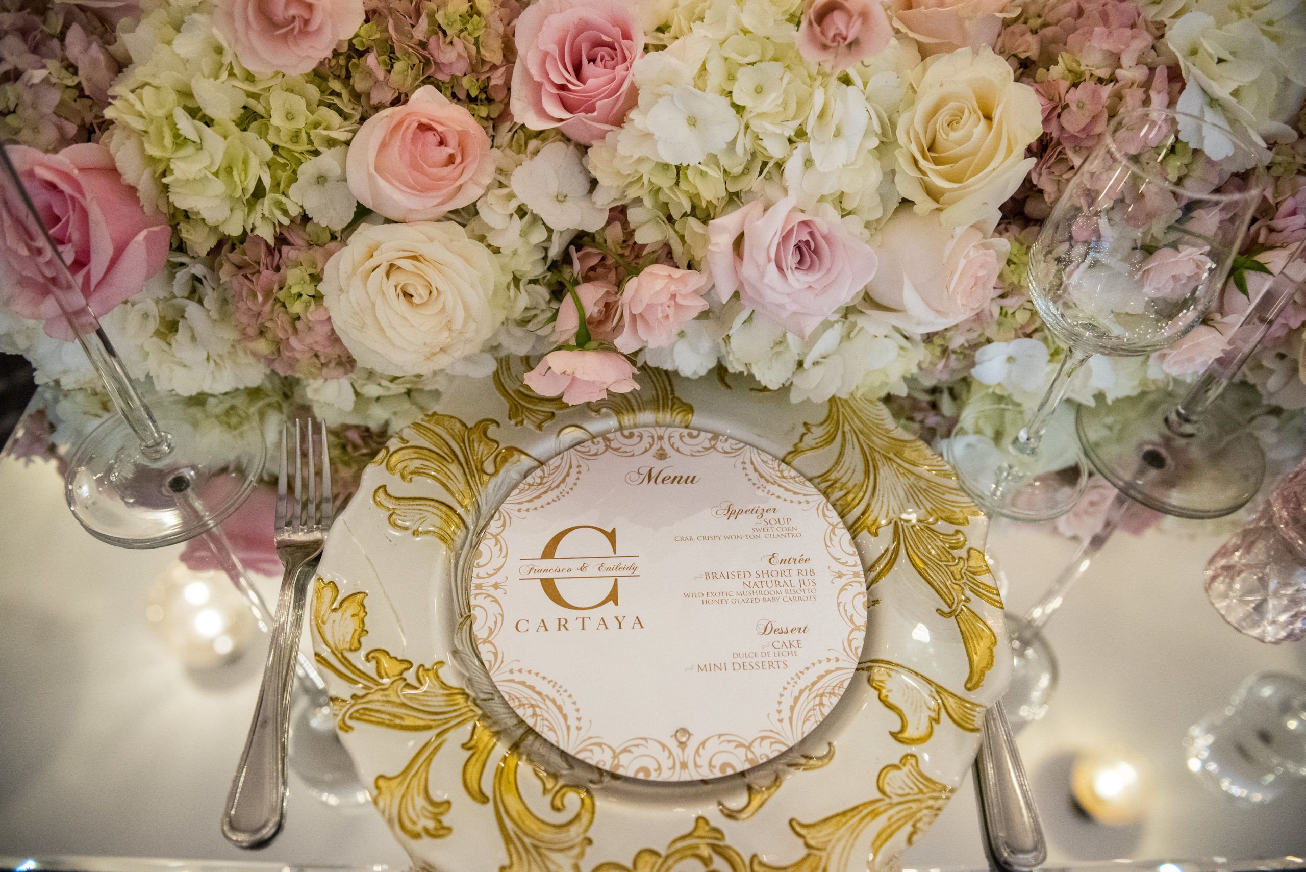 Gold place setting with blush and cream floral centerpieces | PartySlate