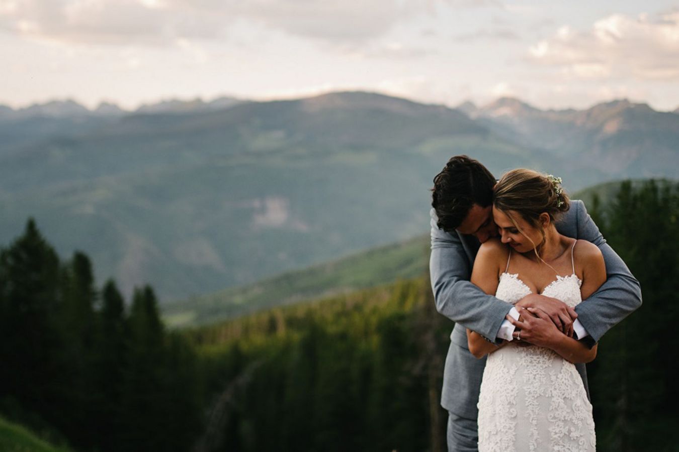 bride and groom posing outside on wedding day in front of mountain view | PartySlate
