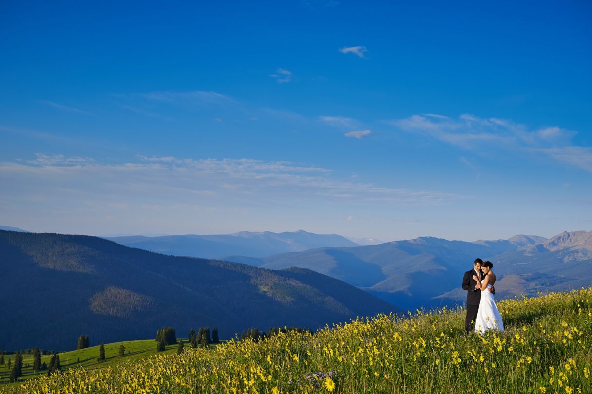 bride and groom posing outside on wedding day in front of mountain view | PartySlate