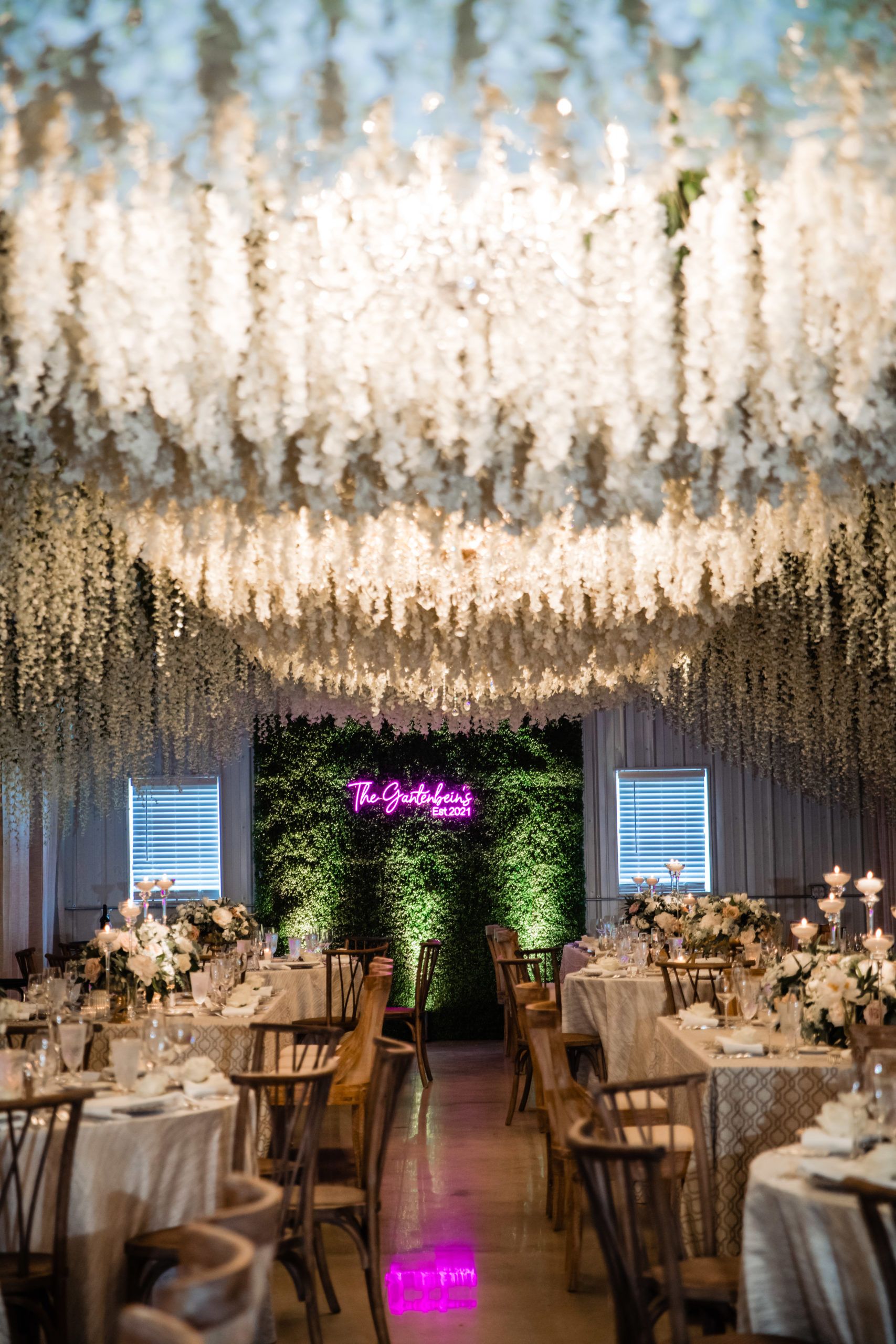 hot pink neon sign at wedding with floral ceiling installation | PartySlate