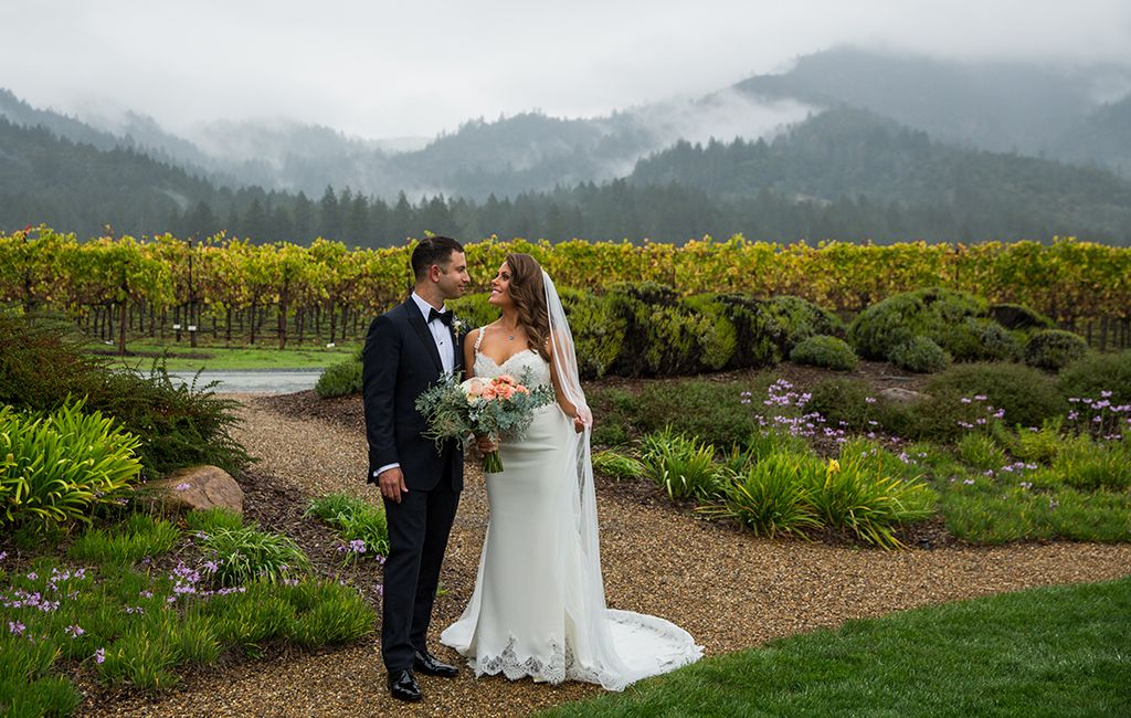 couple standing outside in front of vineyard on their wedding day | PartySlate
