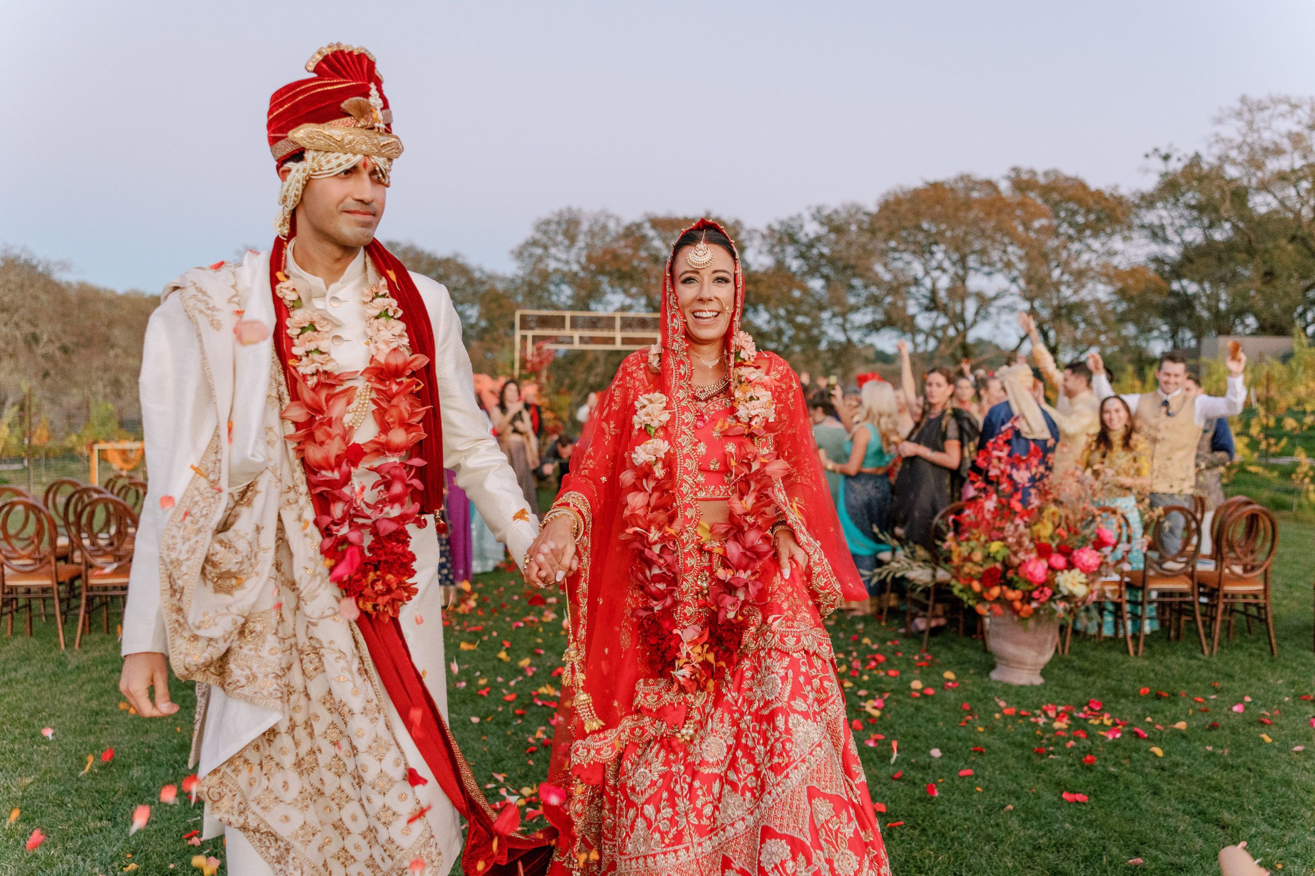 colorful wedding in wine country california with flower petals being thrown over couple as they walk down the aisle | PartySlate