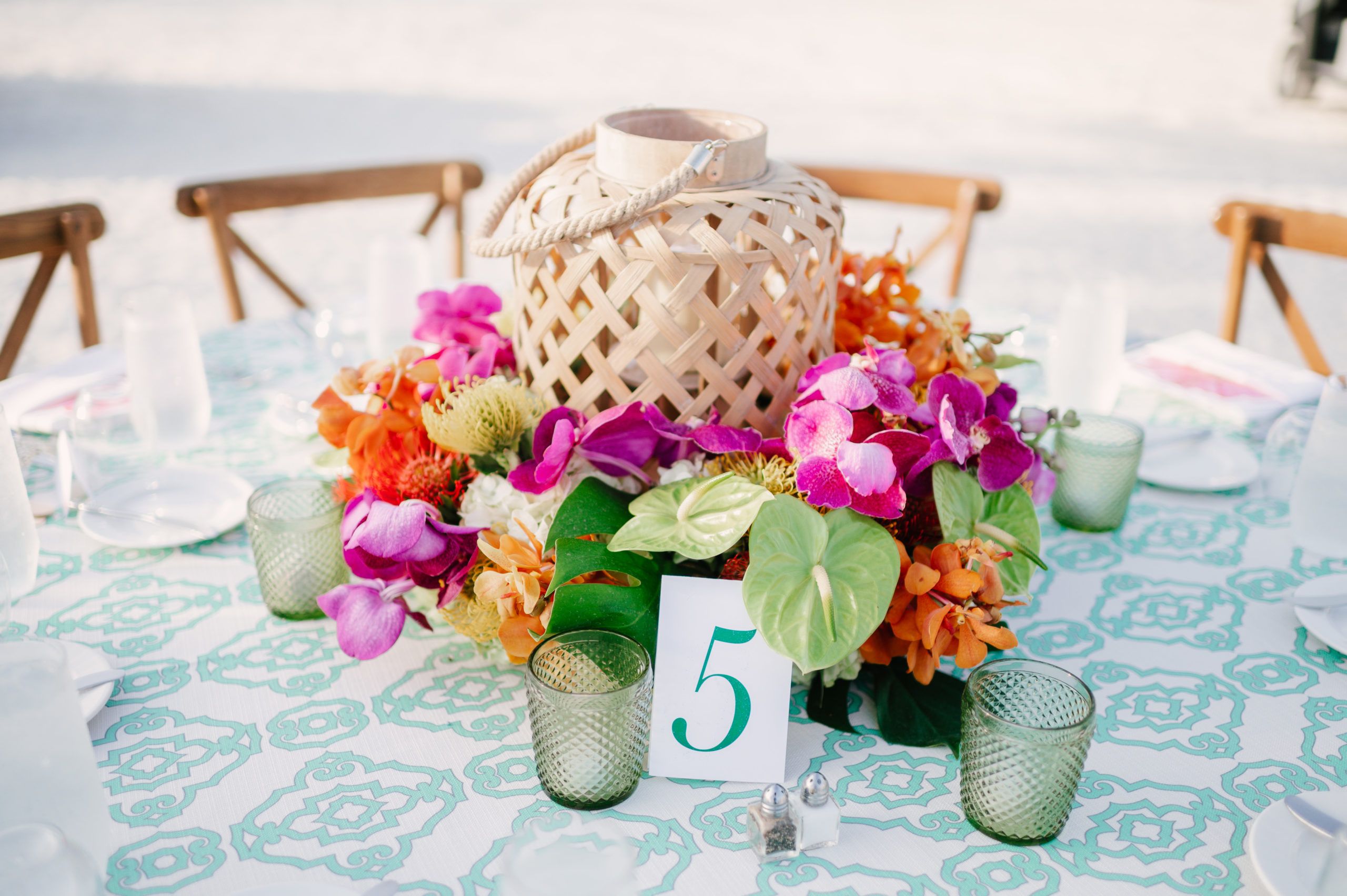 Tropical wicker basket centerpiece surrounded by bright tropical flowers | PartySlate