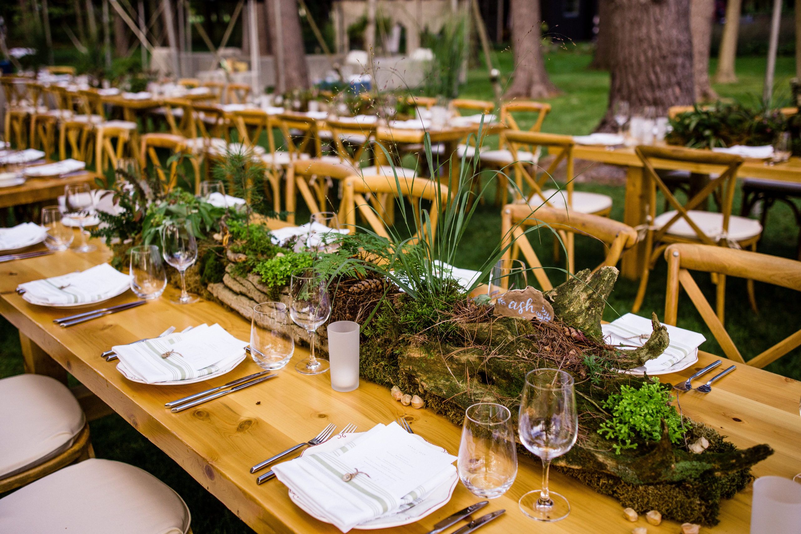 Summer wedding with wooden tables and log centerpieces covered in moss | PartySlate