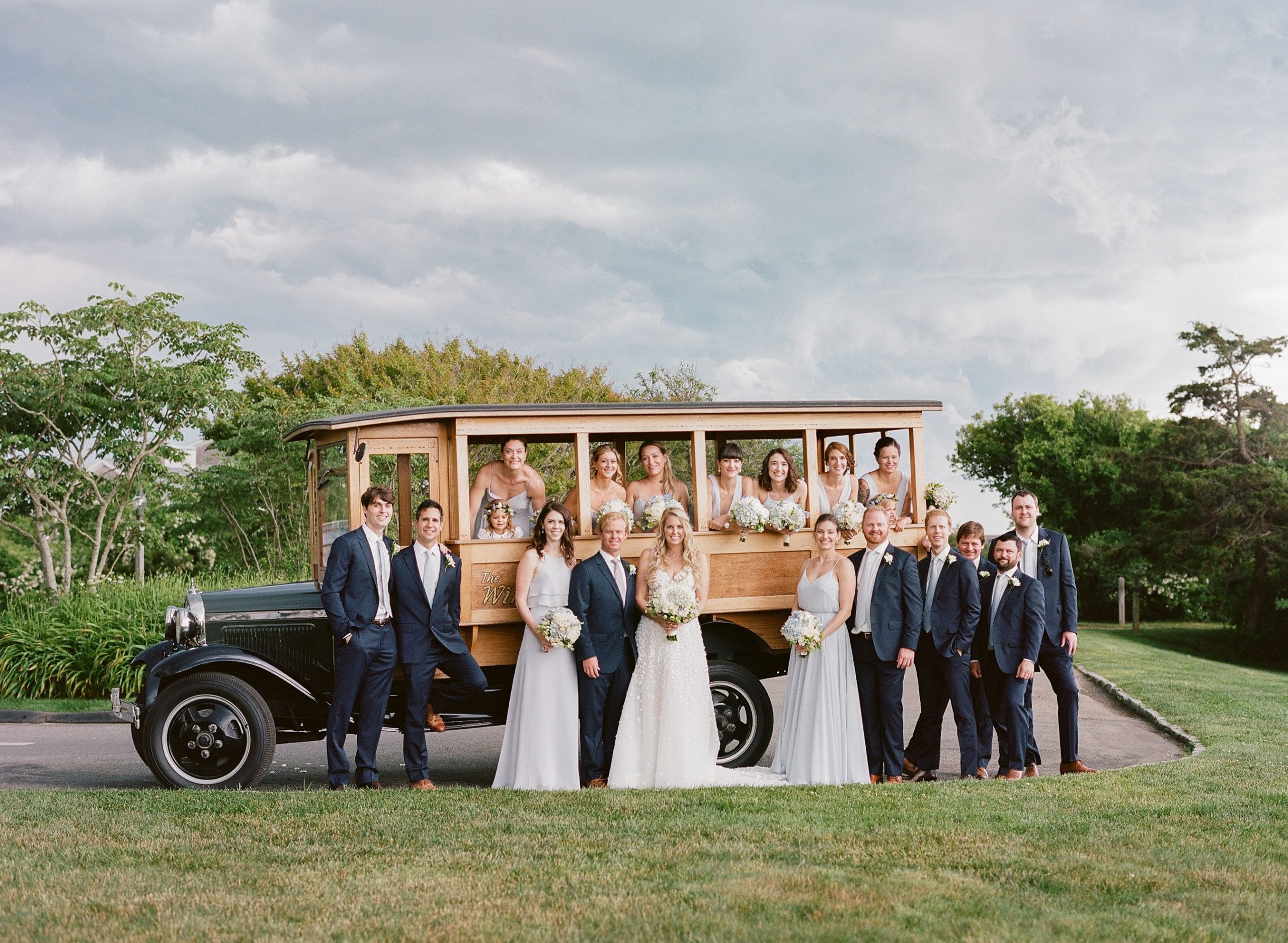 wedding in marthas vineyard with wedding party standing in front of an old car outside | PartySlate