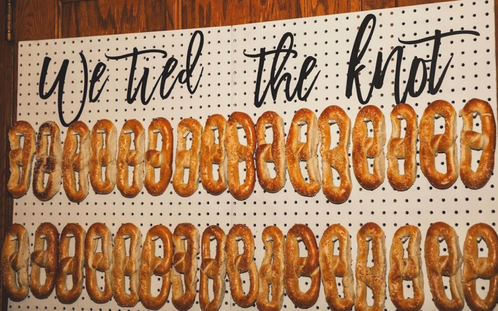 Pretzel wall at a wedding with signage that reads,