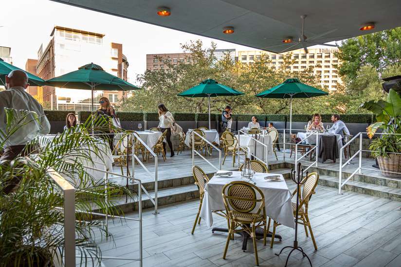 The Annie Cafe & Bar outdoor patio area with tables for dining and green umbrellas | PartySlate