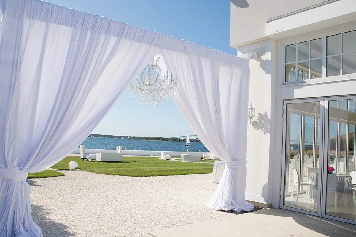 luxury seaside wedding venue Belle Mer in Newport with white draped curtains and outdoor garden space | PartySlate