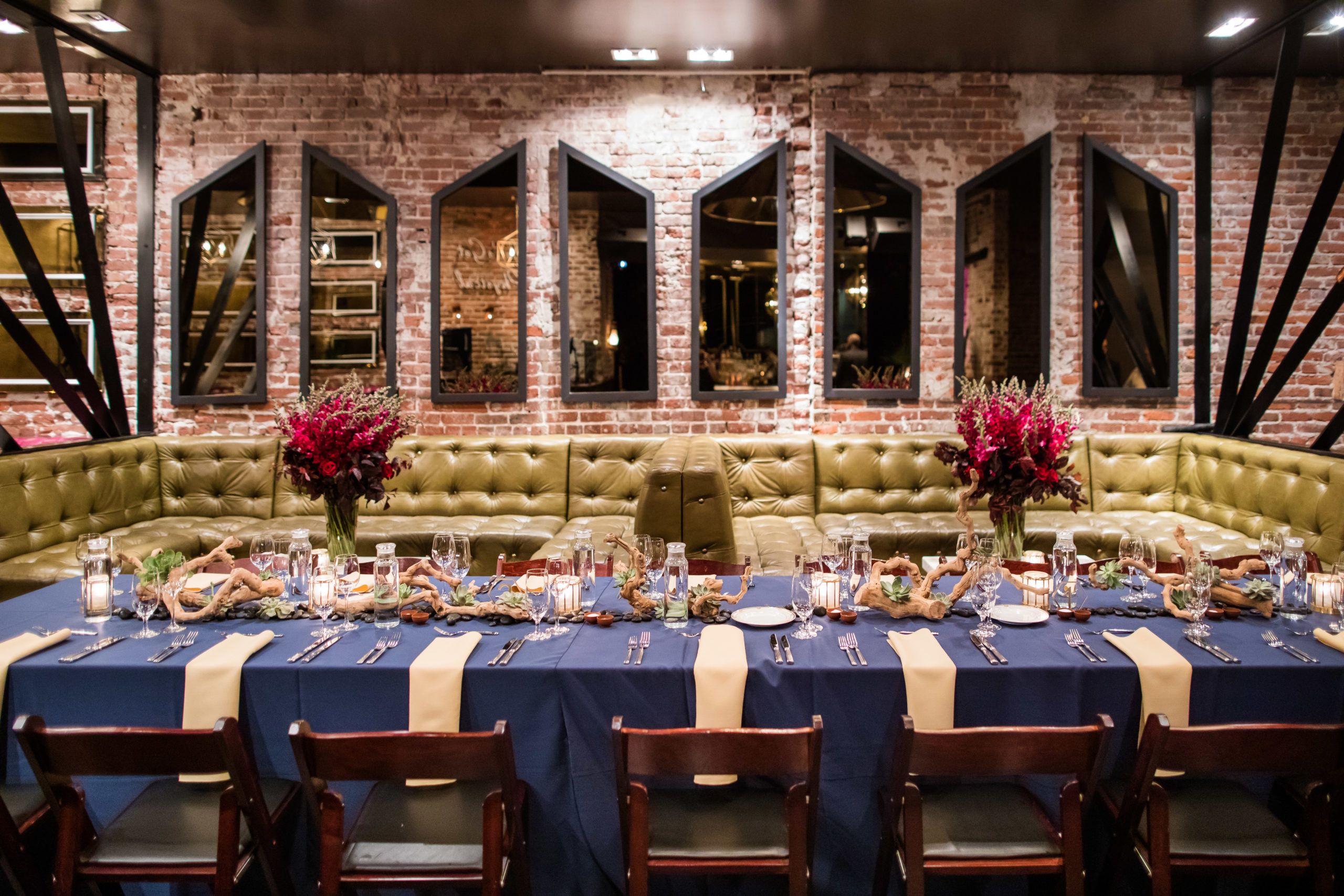 InVision Corporate Seated Dinner at Monroe in San Francisco with green leather booth seating and a long table set with blue linen | PartySlate