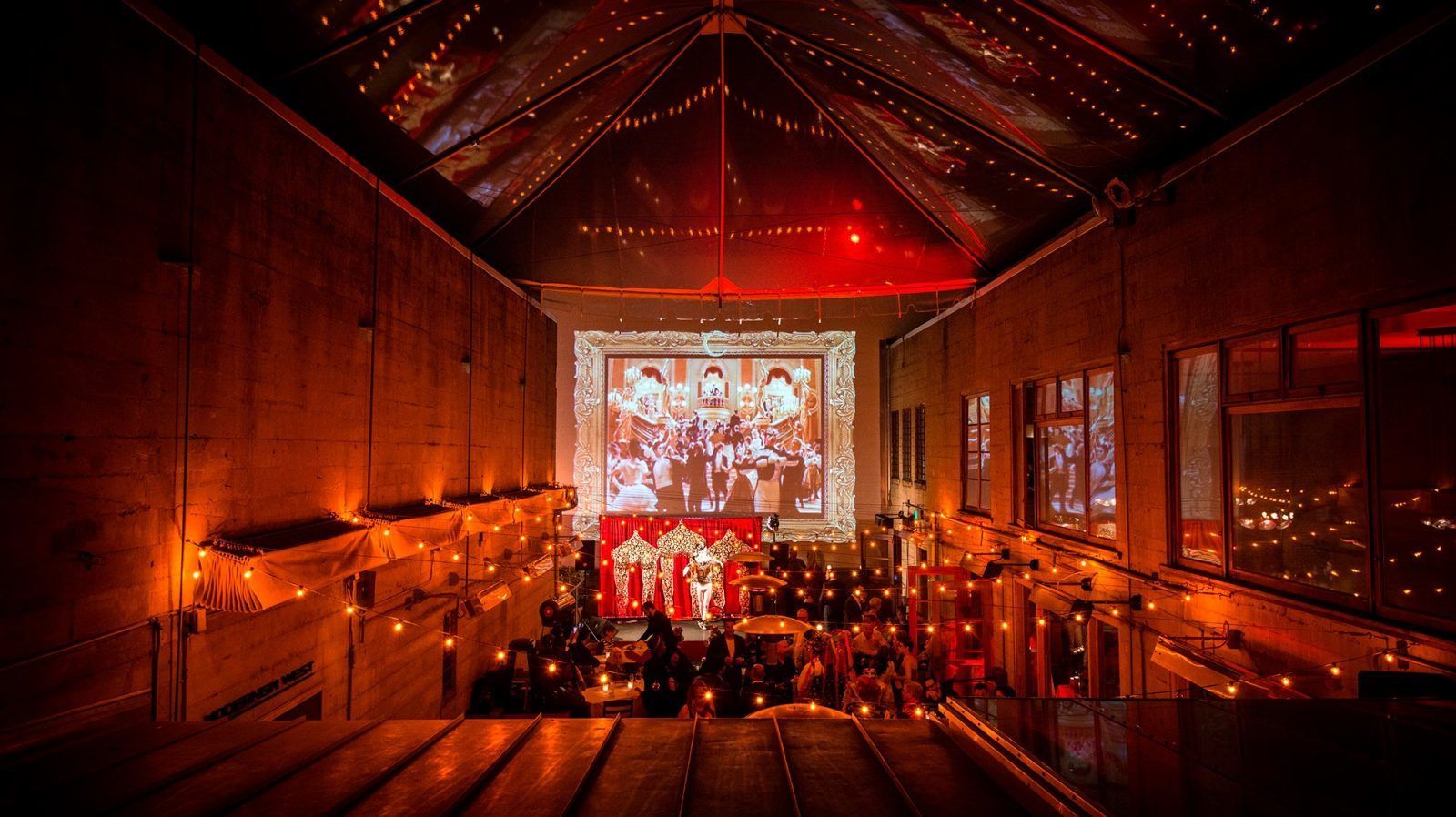 full-restaurant buyout at Foreign Cinema with red lighting and string lights across the room | PartySlate