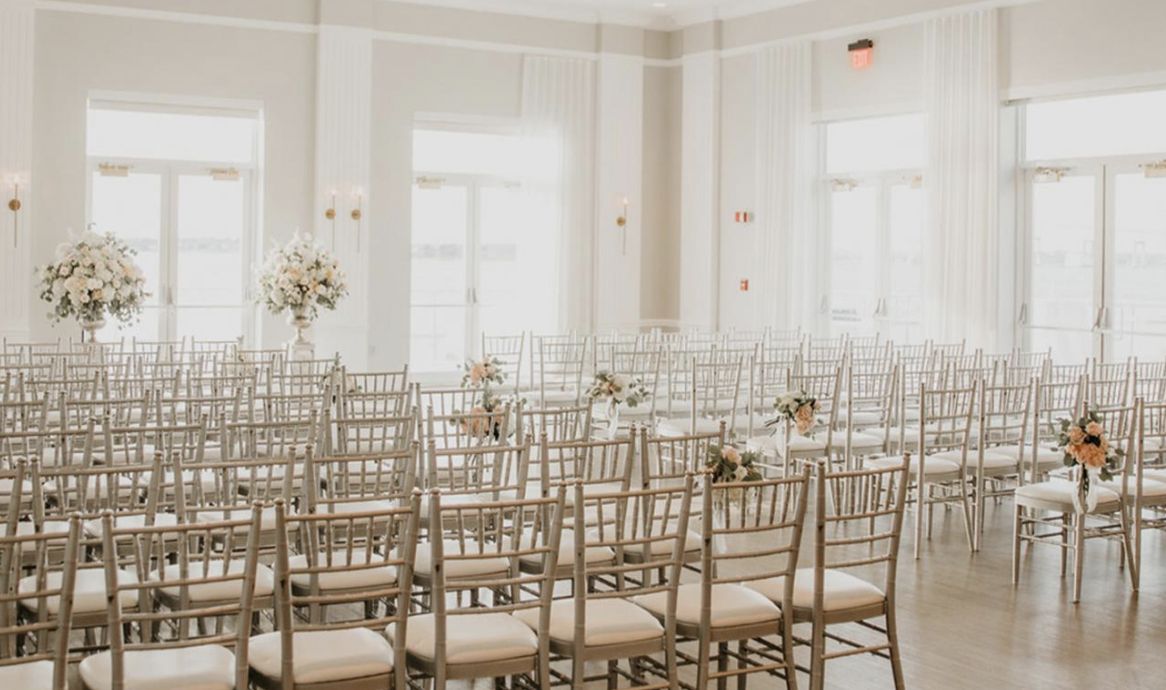 interior wedding ceremony and reception space at Gurney's Newport Resort & Marina in Newport Rhode Island with white washed décor and florals | PartySlate