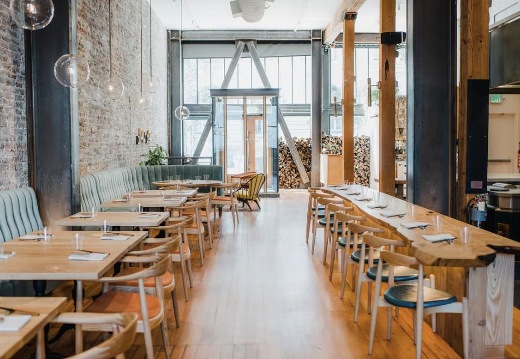 bright and airy private dining space at Birdsong in San Francisco with light wood tables and hanging lights | PartySlate