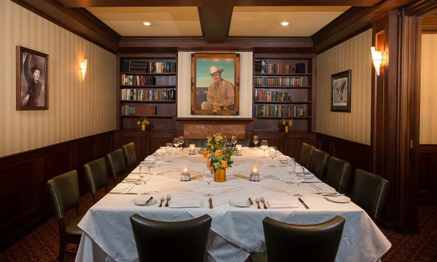 The Library room at Harris' Steakhouse in San Francisco with wood accents and white tables cloth on set table | PartySlate