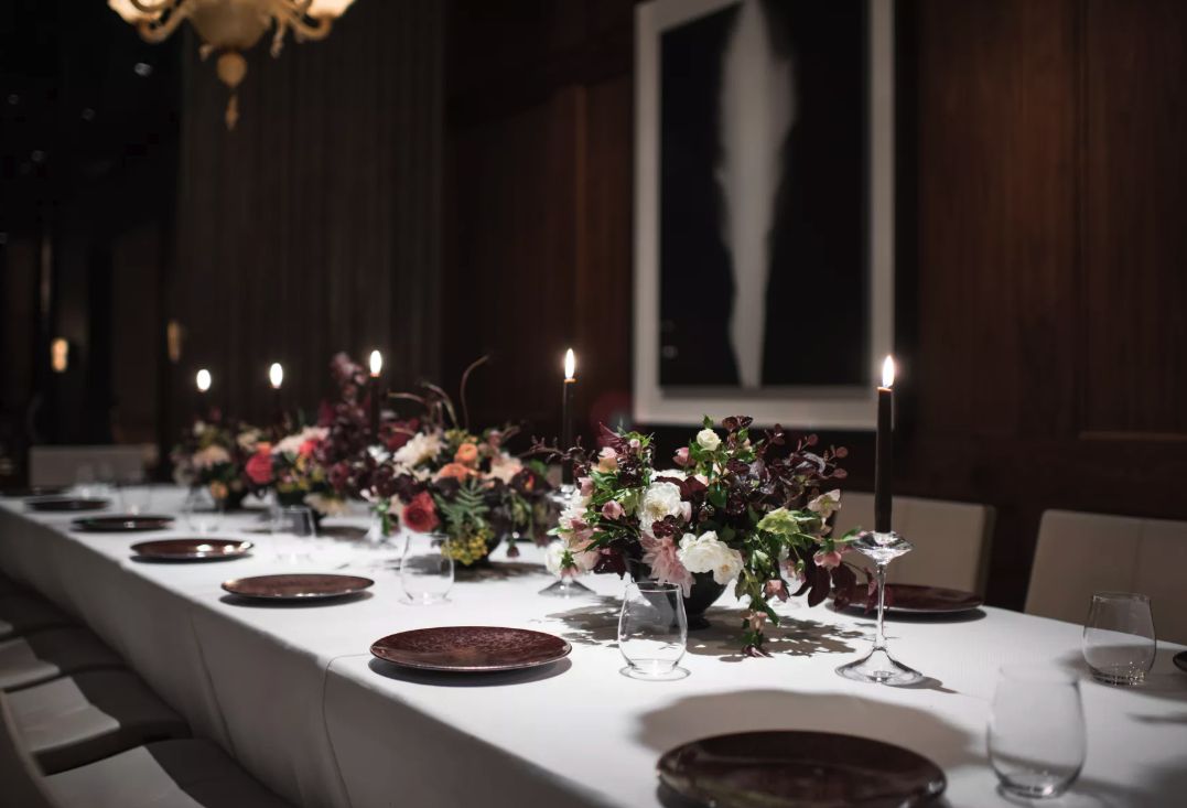 Private dining room at Qince in san francisco with table set with floral centerpieces and tall candle sticks | PartySlate