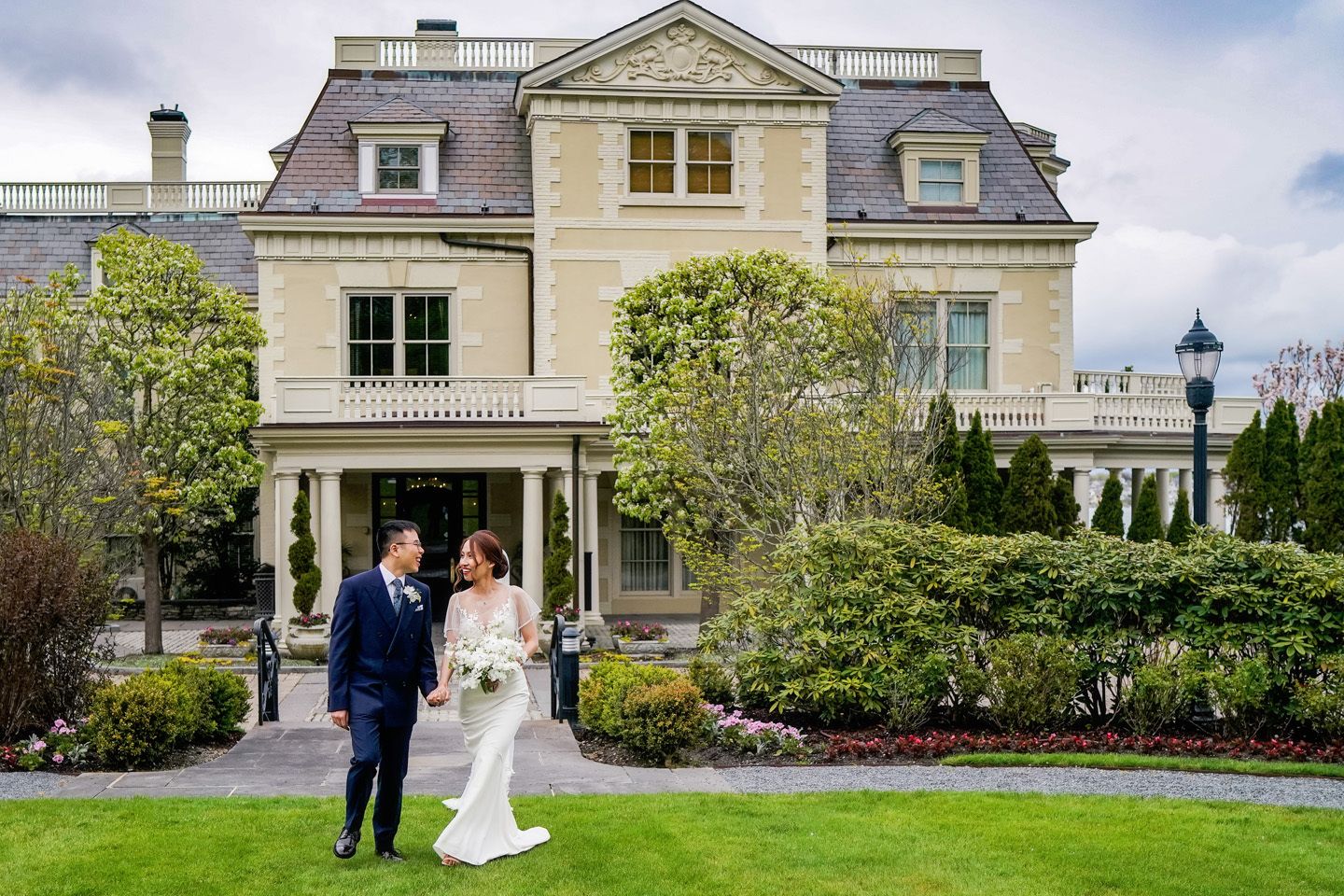 wedding at The Chanler at Cliff Walk with couple walking away from the venue and holding hands | PartySlate