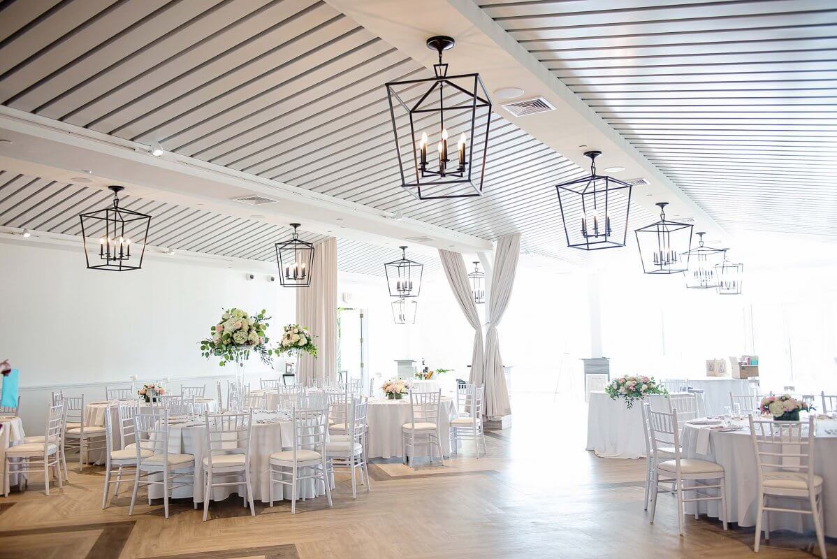 Newport Beach House indoor wedding reception with floral centerpieces on tables | PartySlate