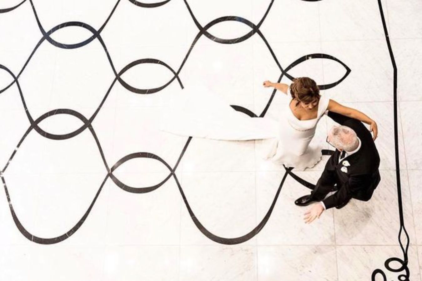 Bride and groom dance on black and white swirly ballroom dance floor at Waldorf Astoria Chicago Hotel | PartySlate