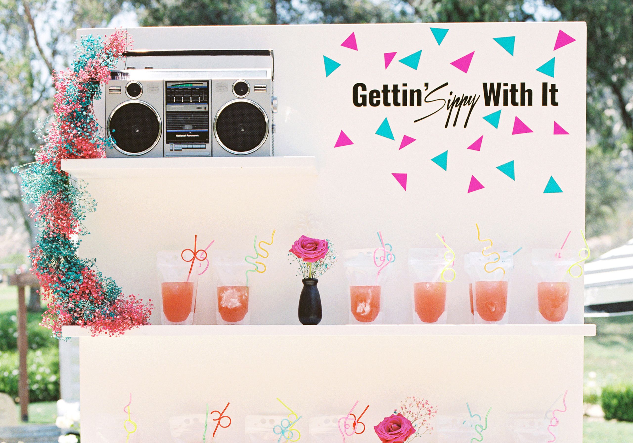Outdoor wedding with 90s-inspired signage and backdrops | PartySlate