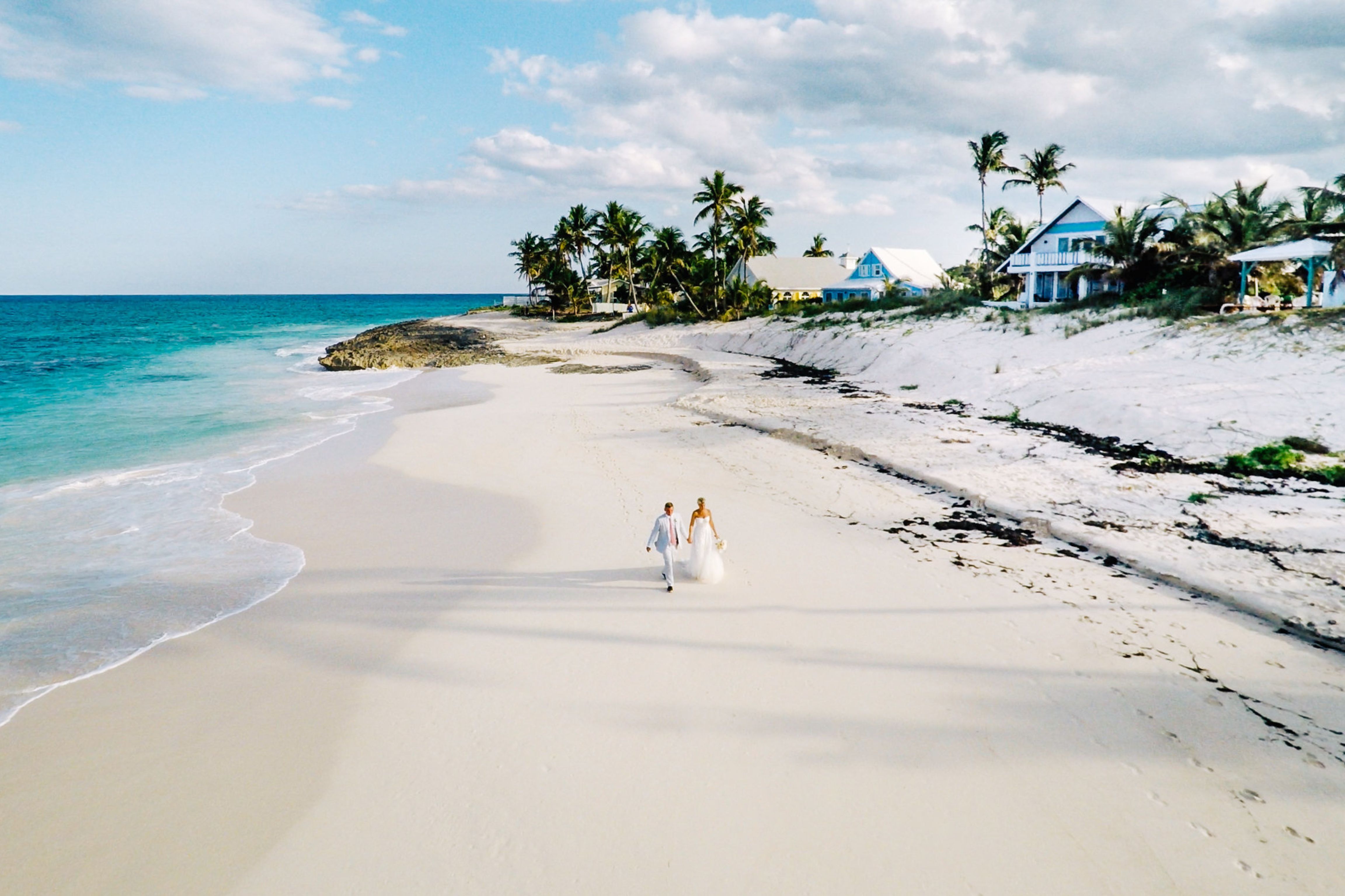 Bride and groom walking on the beach.