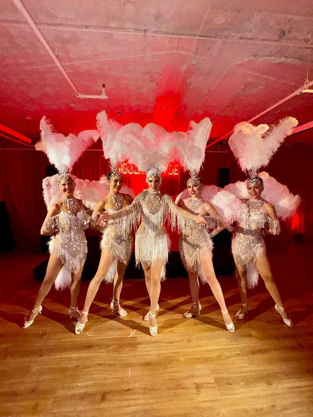 Featured photo from See This Parisian Cabaret–Themed Corporate Event with Feathered Costumes and Dramatic Red Glow